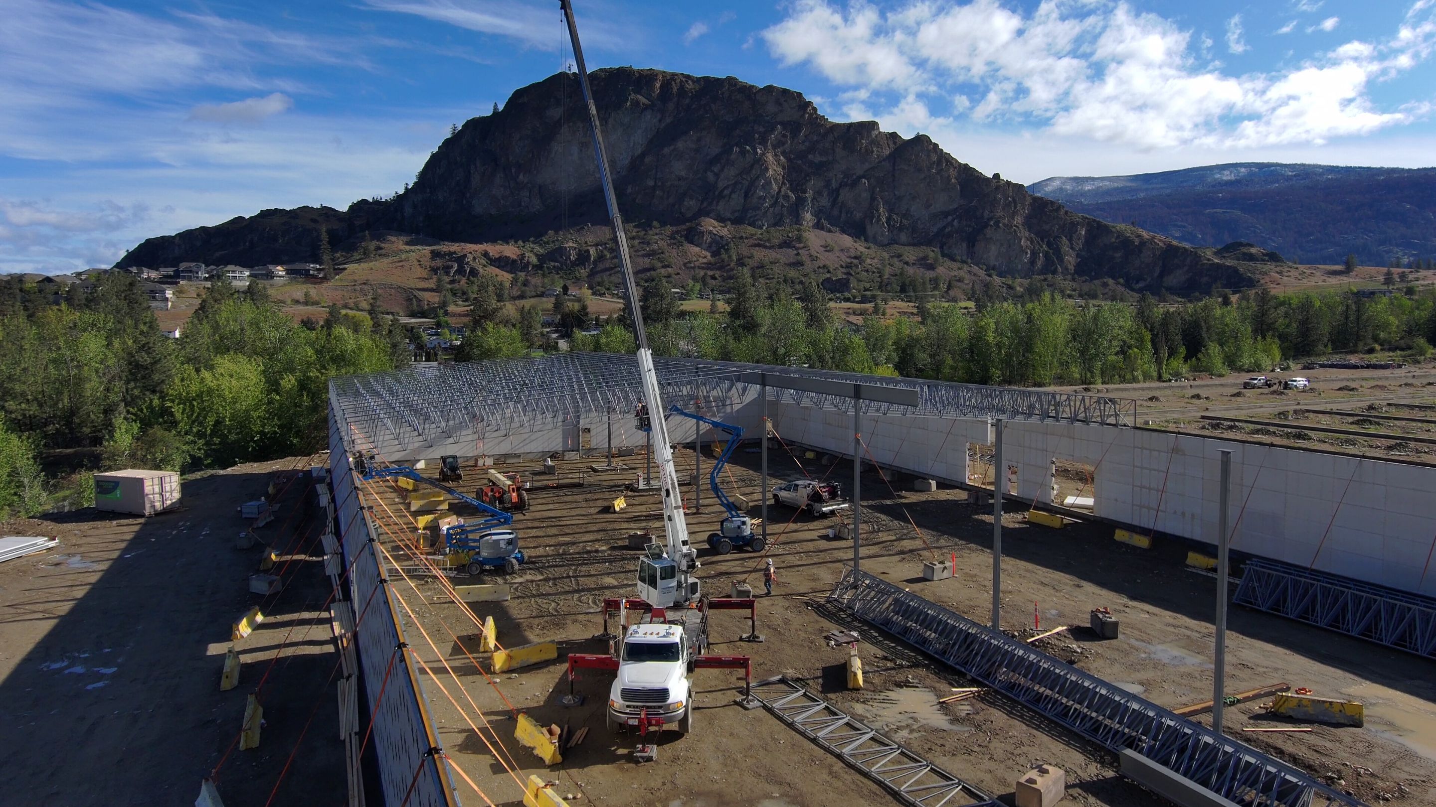 Worker on a lift fastening a prefabricated wall panel to steel framing